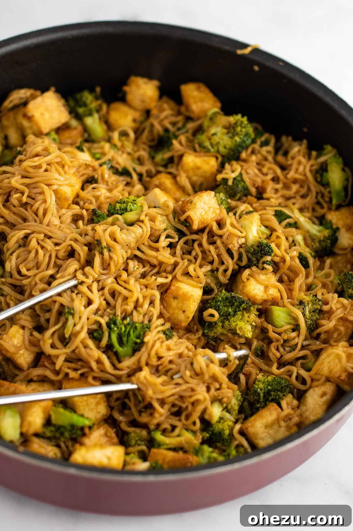 A side view of broccoli tofu ramen noodle stir fry in a pan, showcasing its texture and rich color
