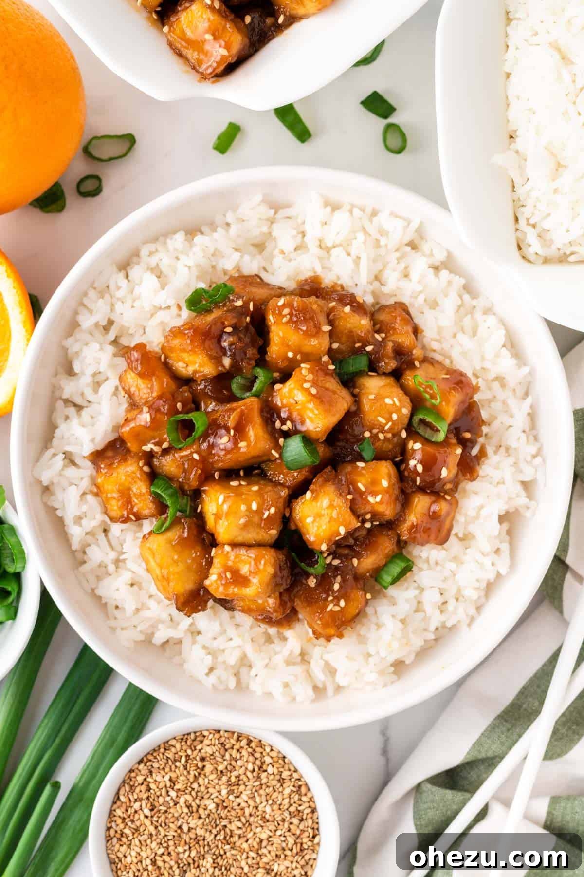 A final appetizing image of orange tofu served over white rice in a bowl, garnished for presentation.