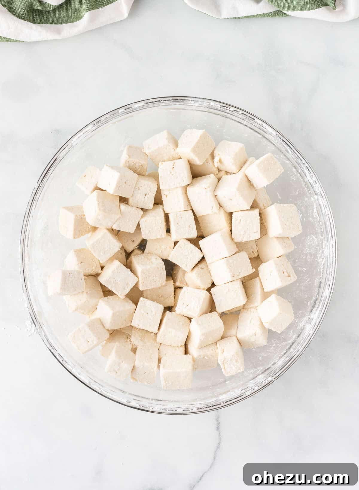 Cubed tofu, now fully and evenly coated in cornstarch, inside a mixing bowl.