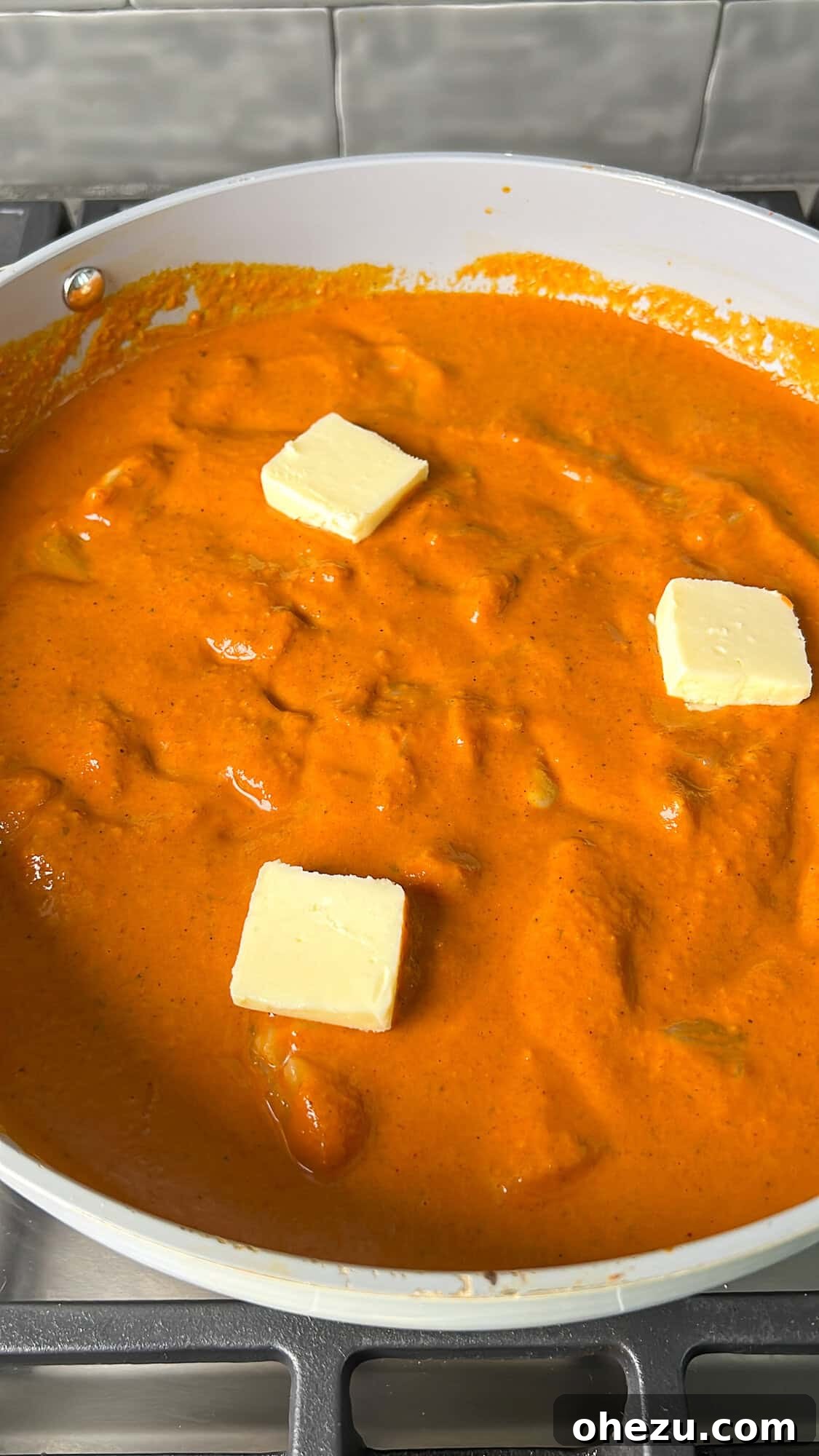 Effortless Butter Chicken 13 A knob of butter being added to the simmering butter chicken, creating a final touch of richness.