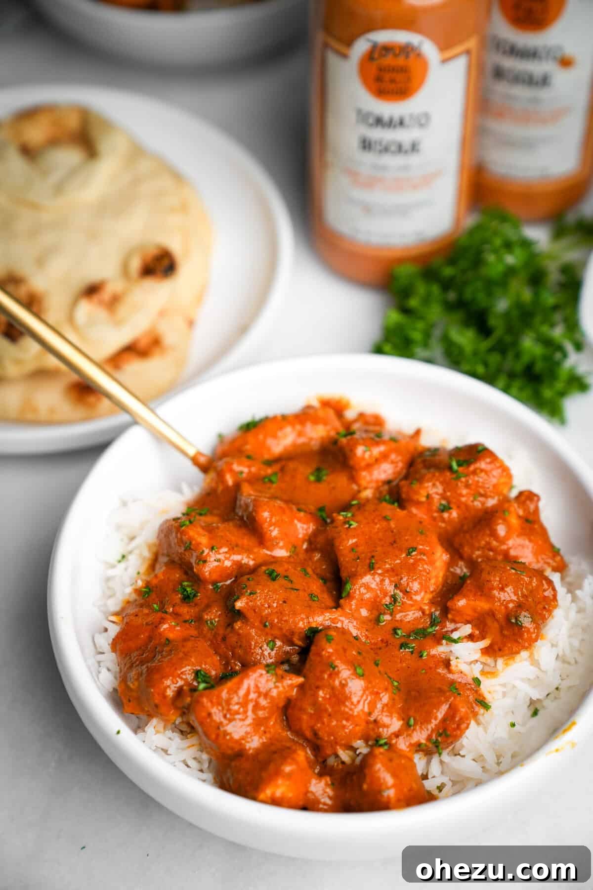 Effortless Butter Chicken 3 A close-up shot of creamy butter chicken in a bowl, accompanied by warm, fluffy naan bread, tempting the viewer to dig in.