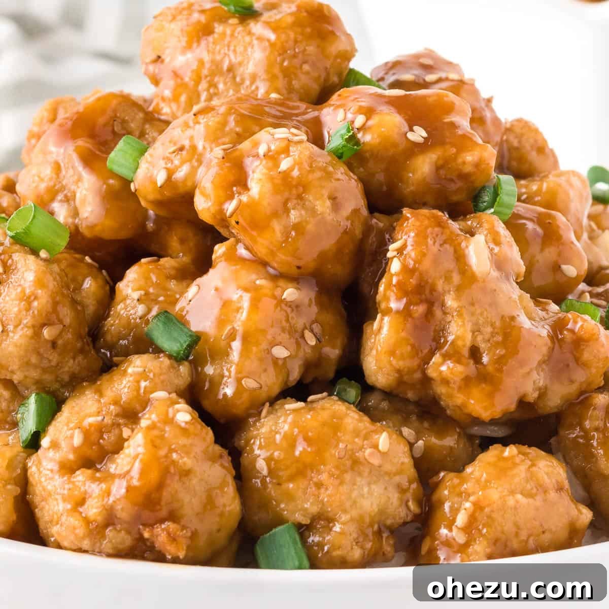 A close-up shot of individual crispy orange cauliflower florets, showing the delicious sauce coating