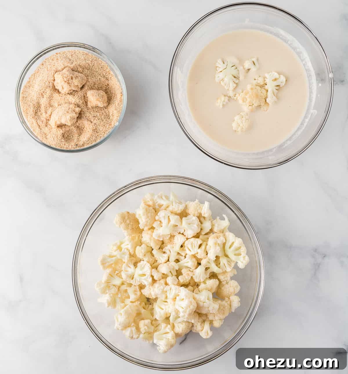 Ingredients laid out for breading cauliflower: a bowl of batter, a bowl of panko bread crumbs, and cauliflower florets