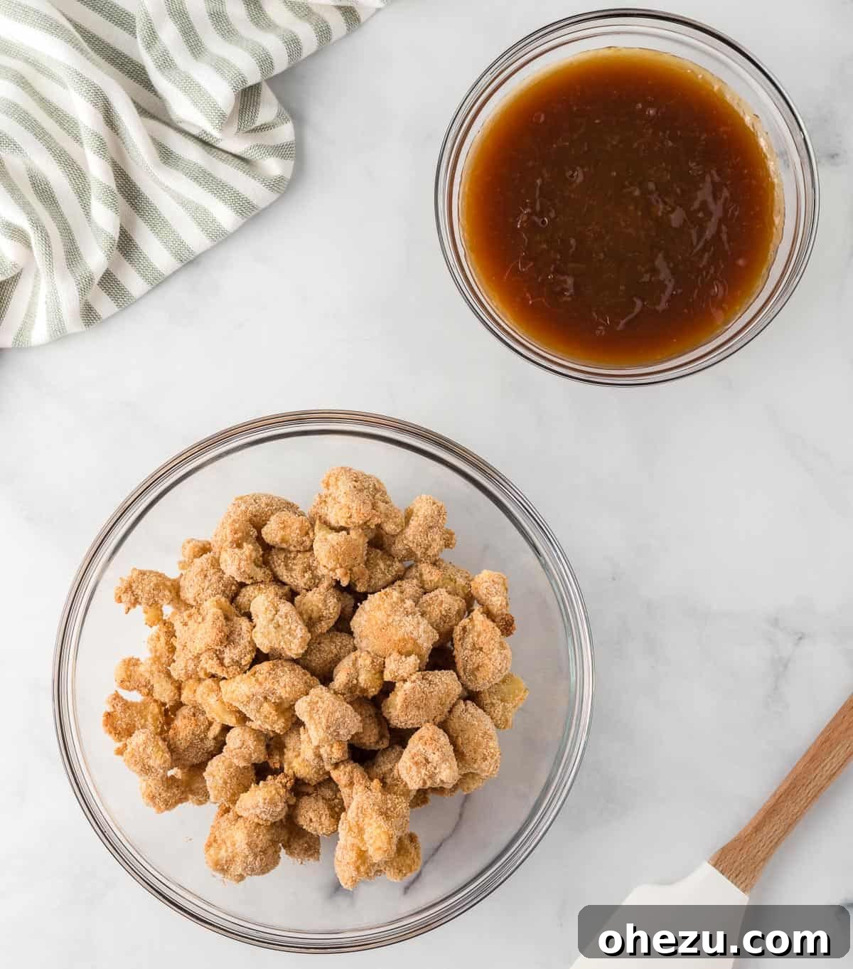 Crispy breaded cauliflower florets in a bowl next to a small bowl of orange sauce
