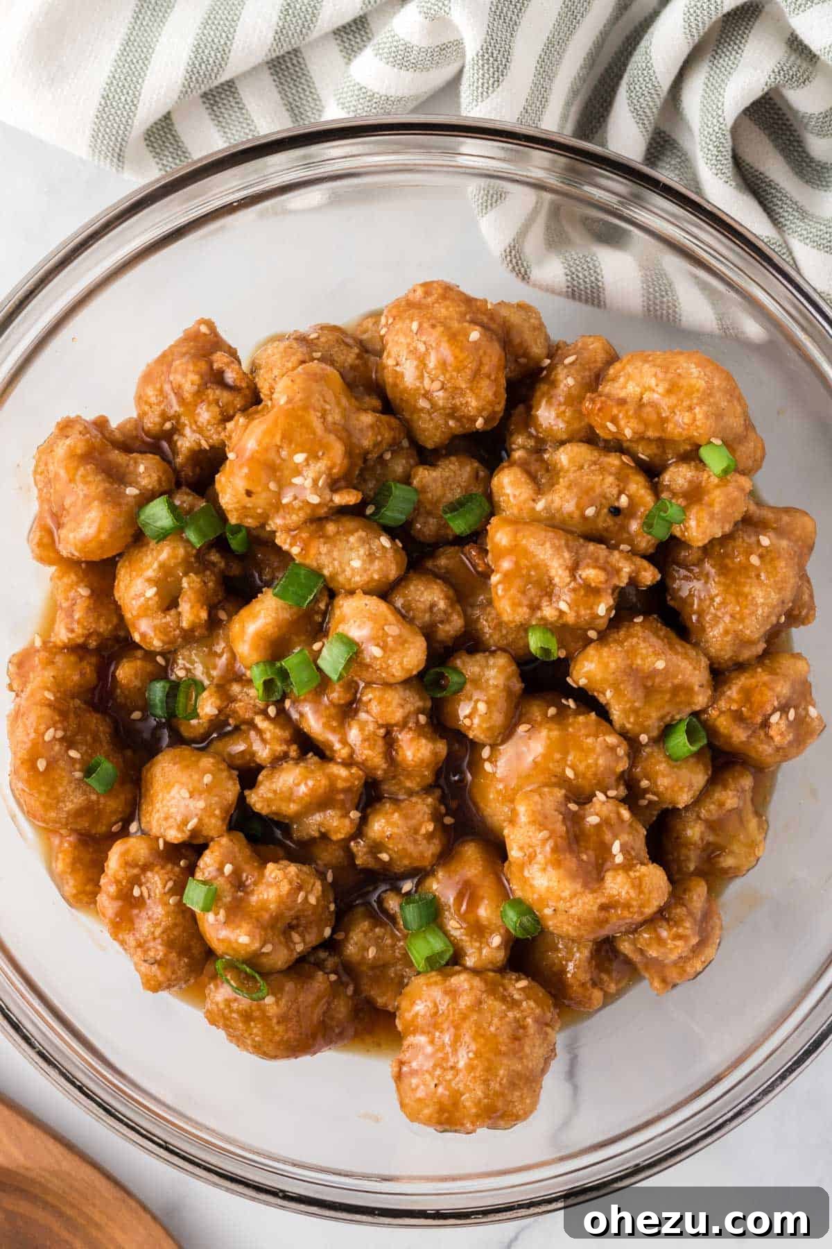 Orange cauliflower in a bowl, generously topped with fresh green onions
