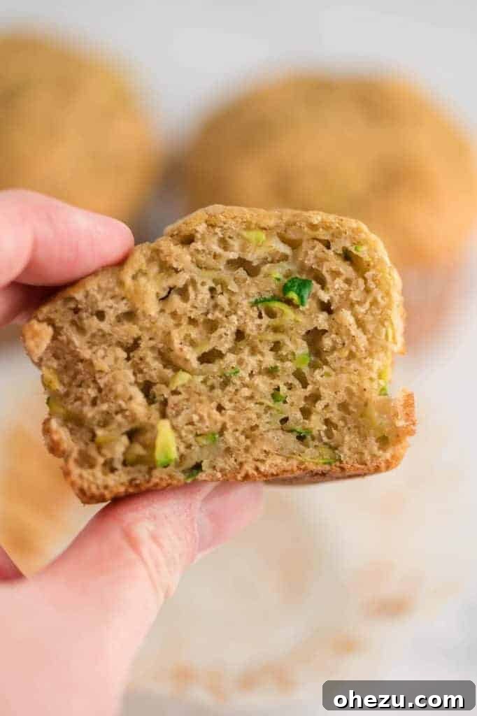 A close-up shot of a zucchini muffin sliced in half, revealing its moist and tender crumb texture, ready to be eaten.
