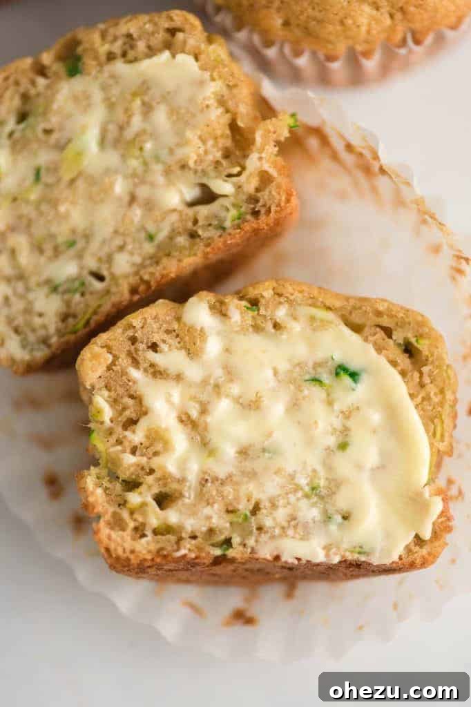 Another enticing view of a zucchini muffin, perfectly cut in half, highlighting its moist and tender texture and the appealing golden-brown crust.