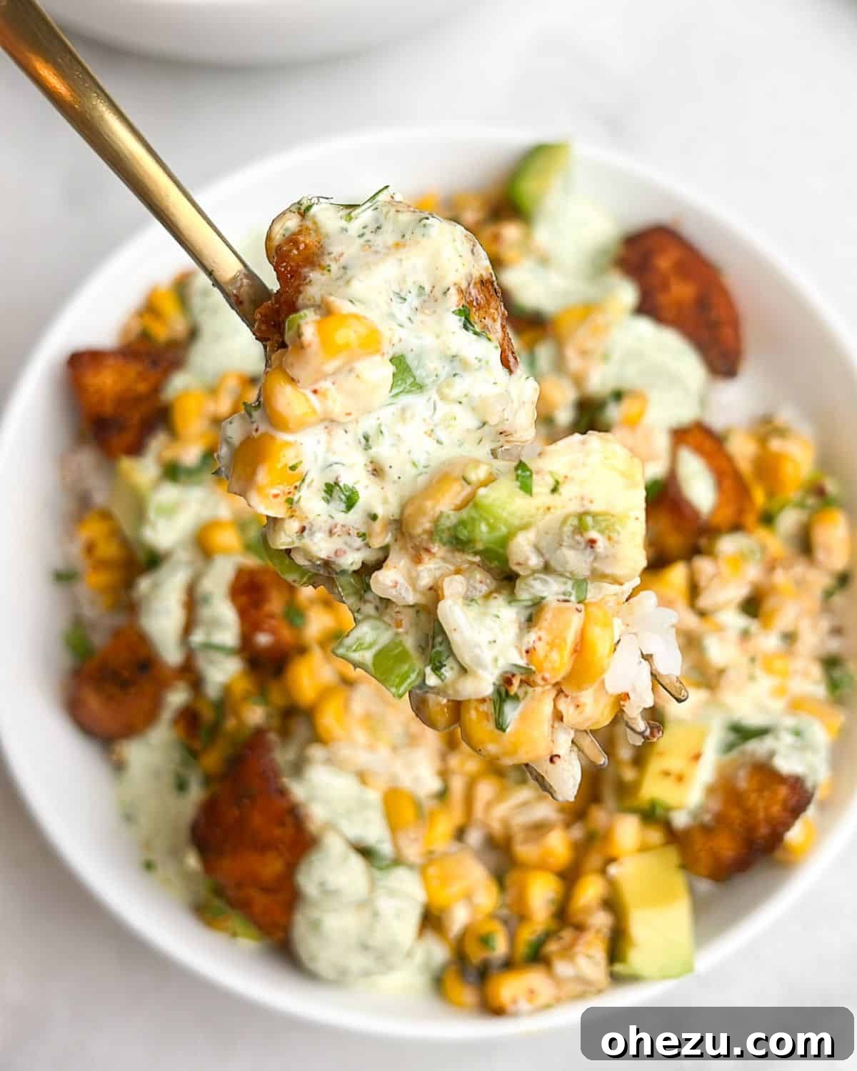 Zesty Street Corn Chicken Bowls 5 A close-up of a spoon lifting street corn and blackened chicken from a vibrant bowl.
