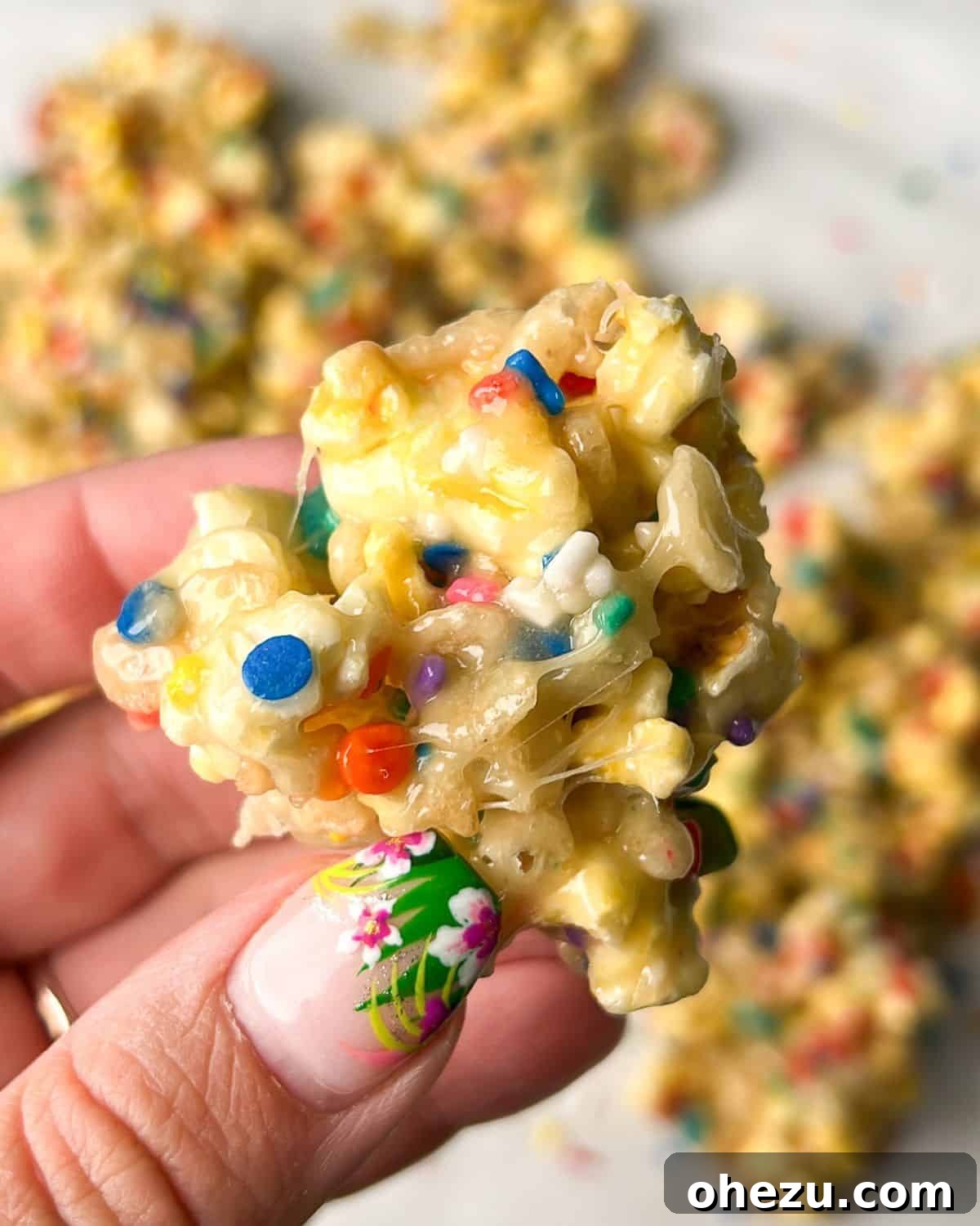 Birthday Cake Popcorn 2 A hand holding a handful of colorful Funfetti Cake Batter Popcorn, showing off its vibrant sprinkles and delightful texture.