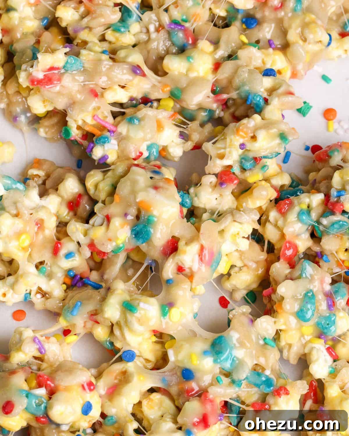 Birthday Cake Popcorn 4 Close-up of freshly made funfetti popcorn cooling on parchment paper, showcasing its colorful sprinkles and sticky texture.