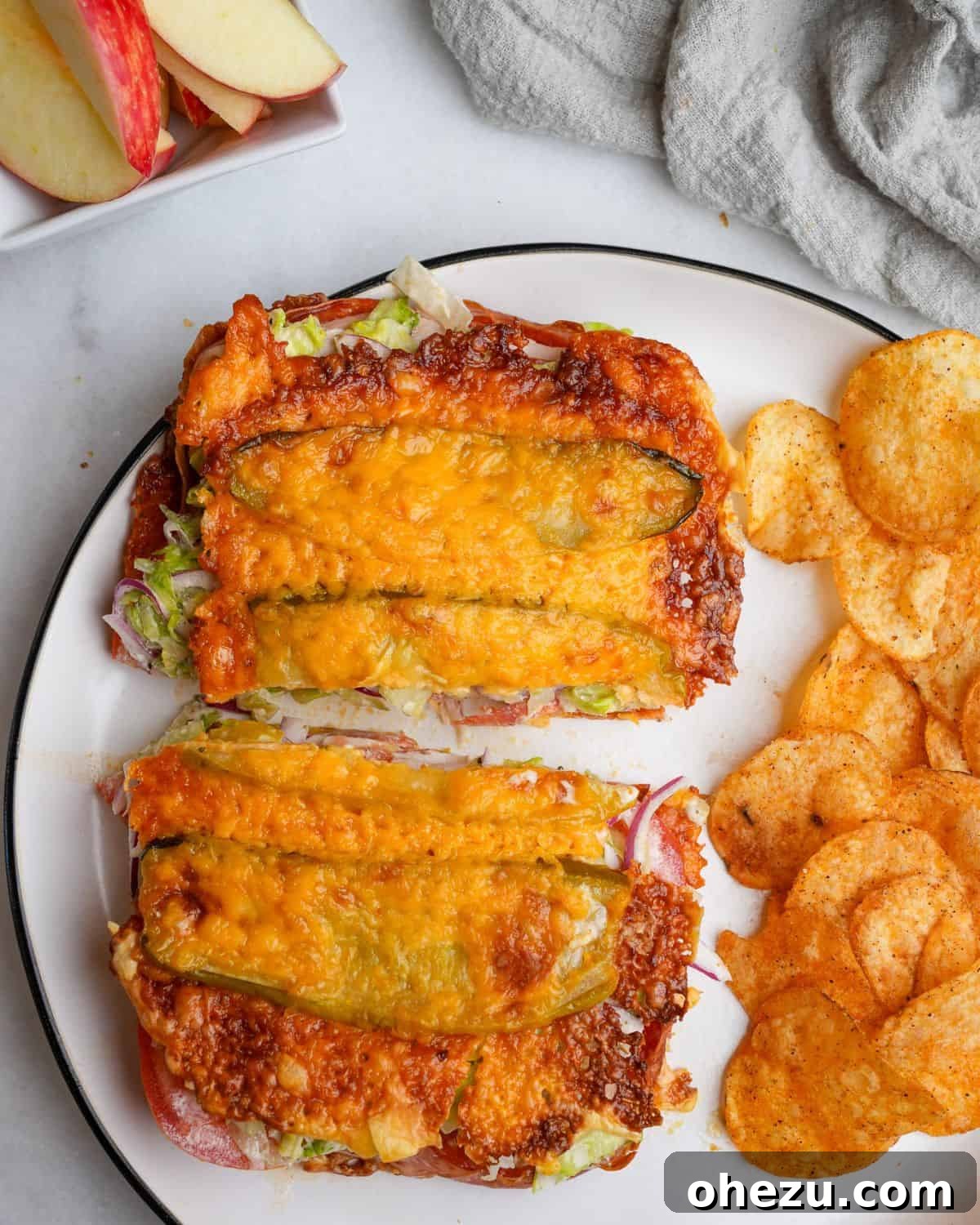 A vibrant Viral Pickle Sandwich resting on a plate, surrounded by crunchy potato chips, showcasing its golden-brown cheese crust.