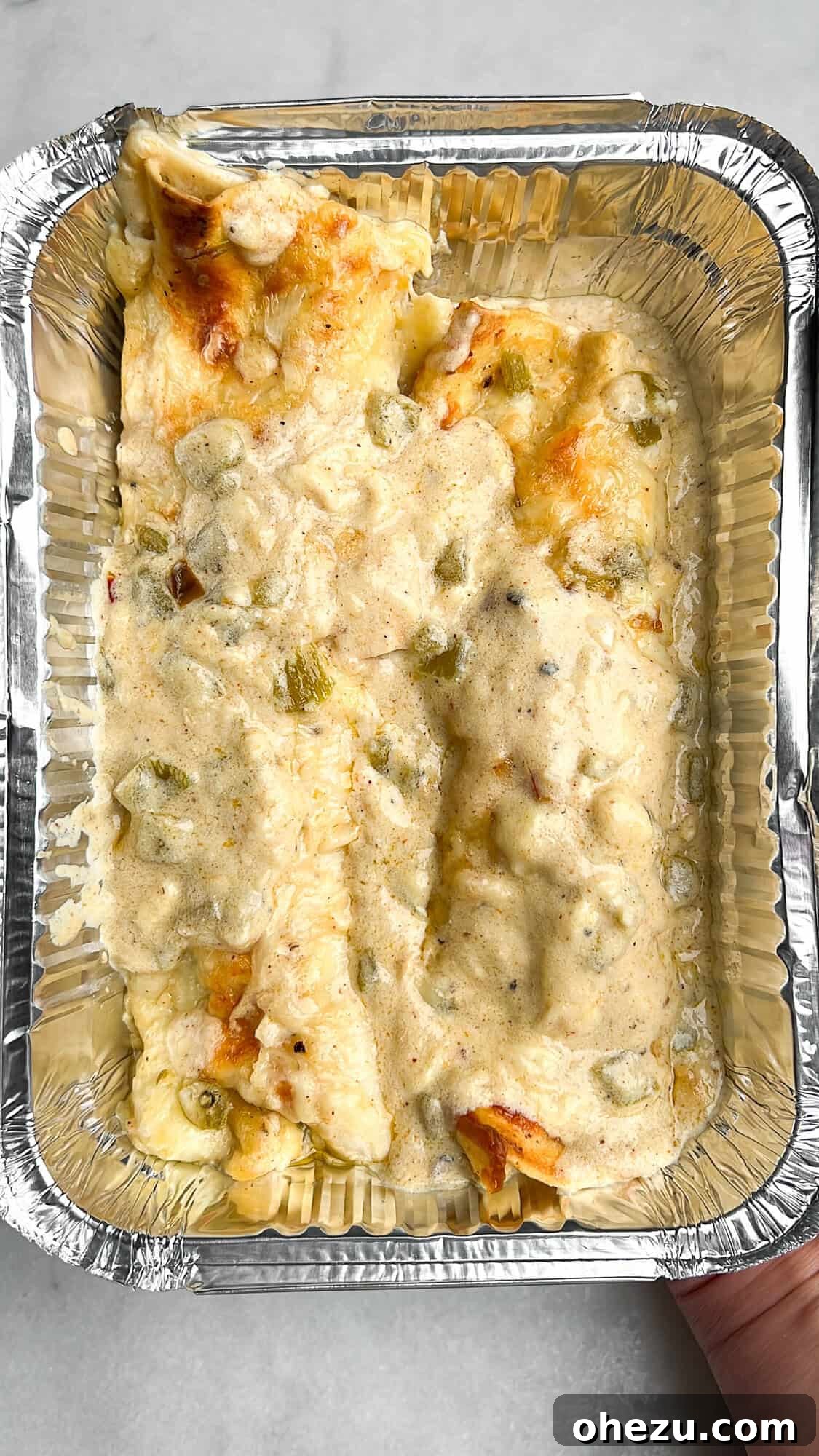 Southwestern Green Chile Chicken Enchiladas 10 Freezer-friendly green chile chicken enchiladas neatly packaged in a disposable aluminum foil container, ready for storage or future reheating, perfect for meal prep.