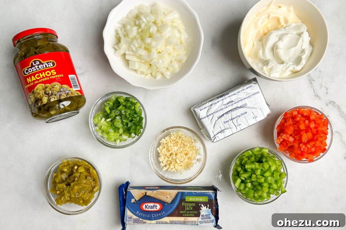 Various fresh ingredients for hot corn dip laid out on a kitchen counter, including corn on the cob, bell peppers, onions, garlic, cream cheese, and mayonnaise.
