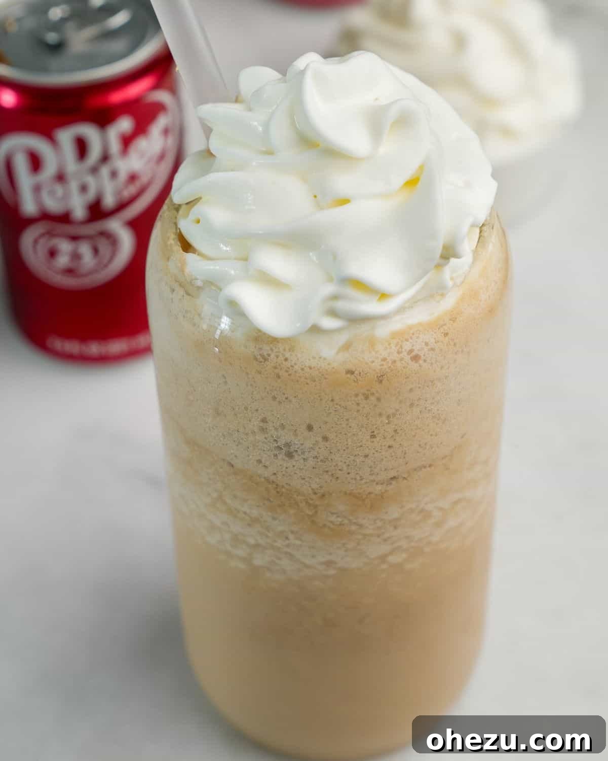 A refreshing glass of creamy frozen whipped Dr. Pepper topped with a swirl of whipped cream.