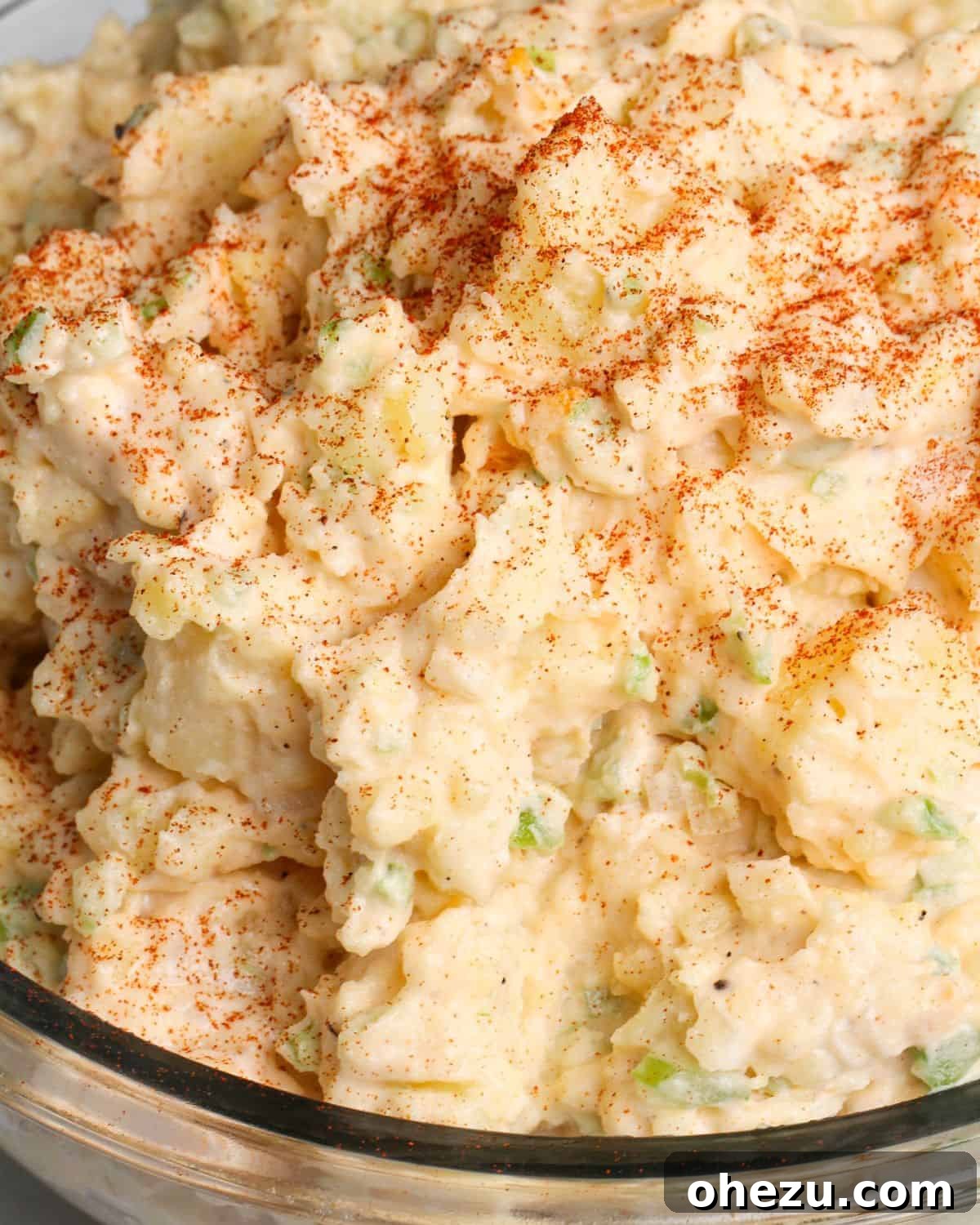 A large, perfectly prepared bowl of eggless potato salad, ready to be served at a picnic or family meal.