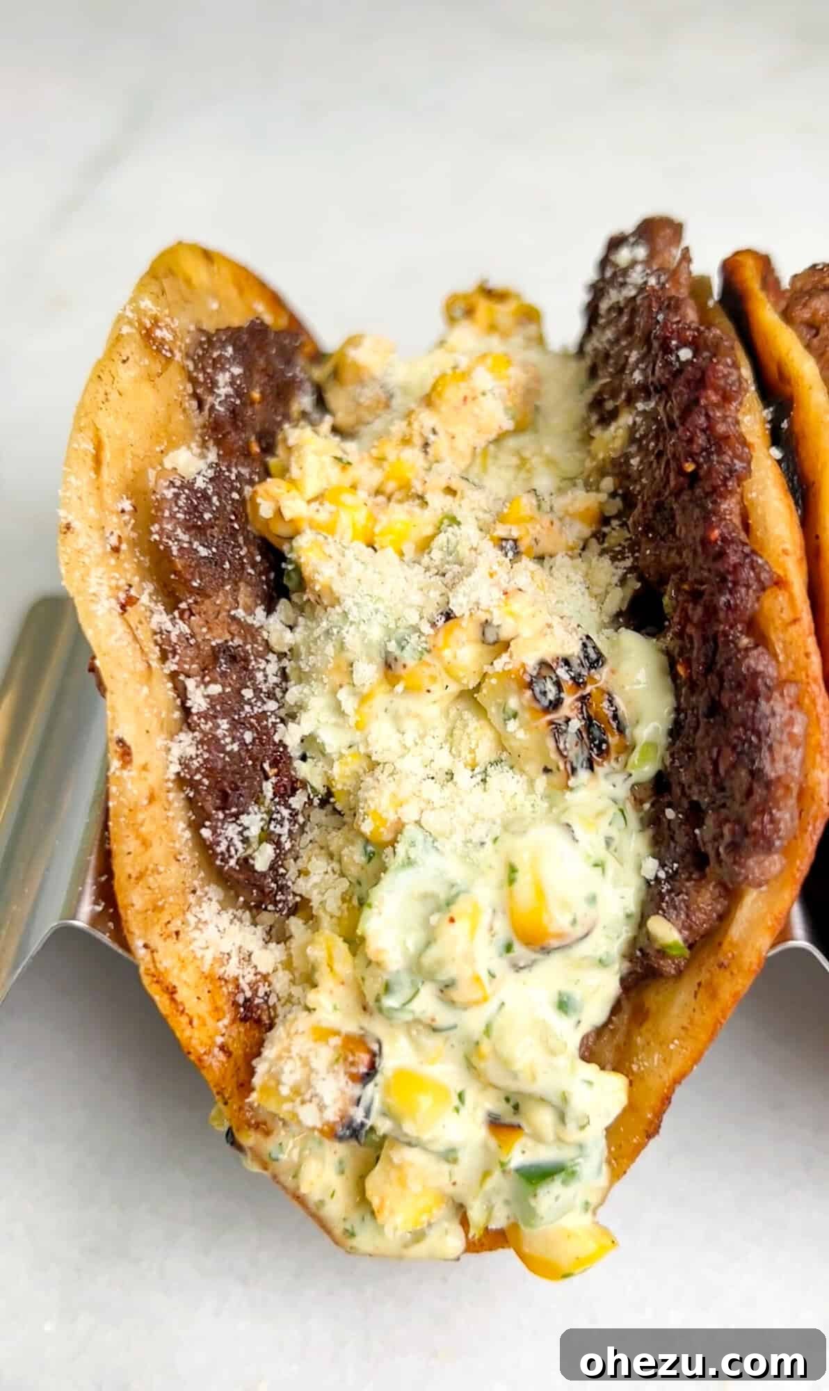 Two Street Corn Smash Burger Tacos filled with meat, corn, and creamy sauce.