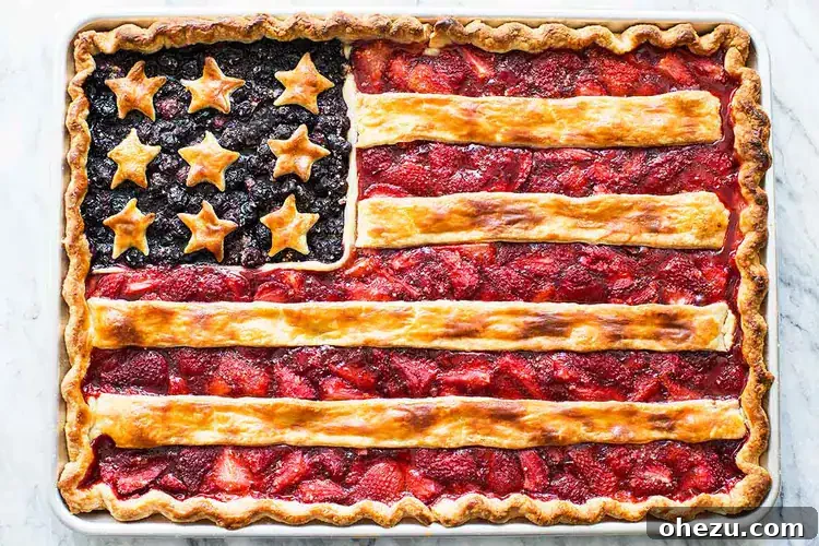 A festive American Flag Slab Pie decorated with blueberries and strawberries in a patriotic design.