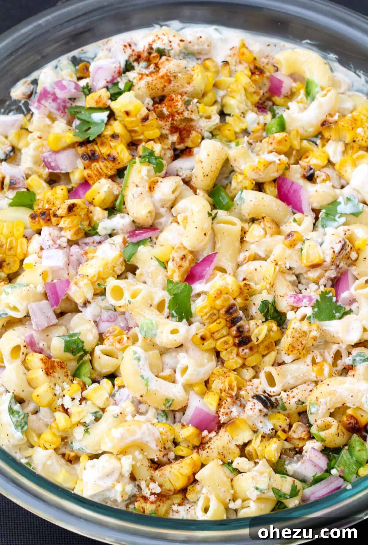 A bowl of creamy Street Corn Elote Pasta Salad garnished with fresh cilantro and lime.
