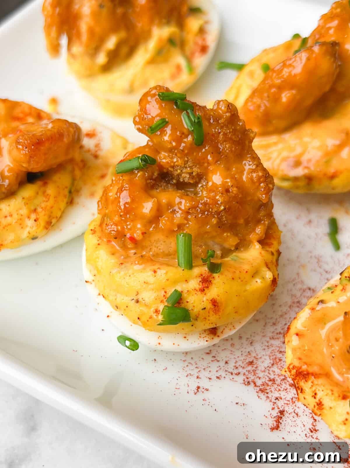Gourmet Firecracker Shrimp Deviled Eggs garnished with green onions and chili flakes.