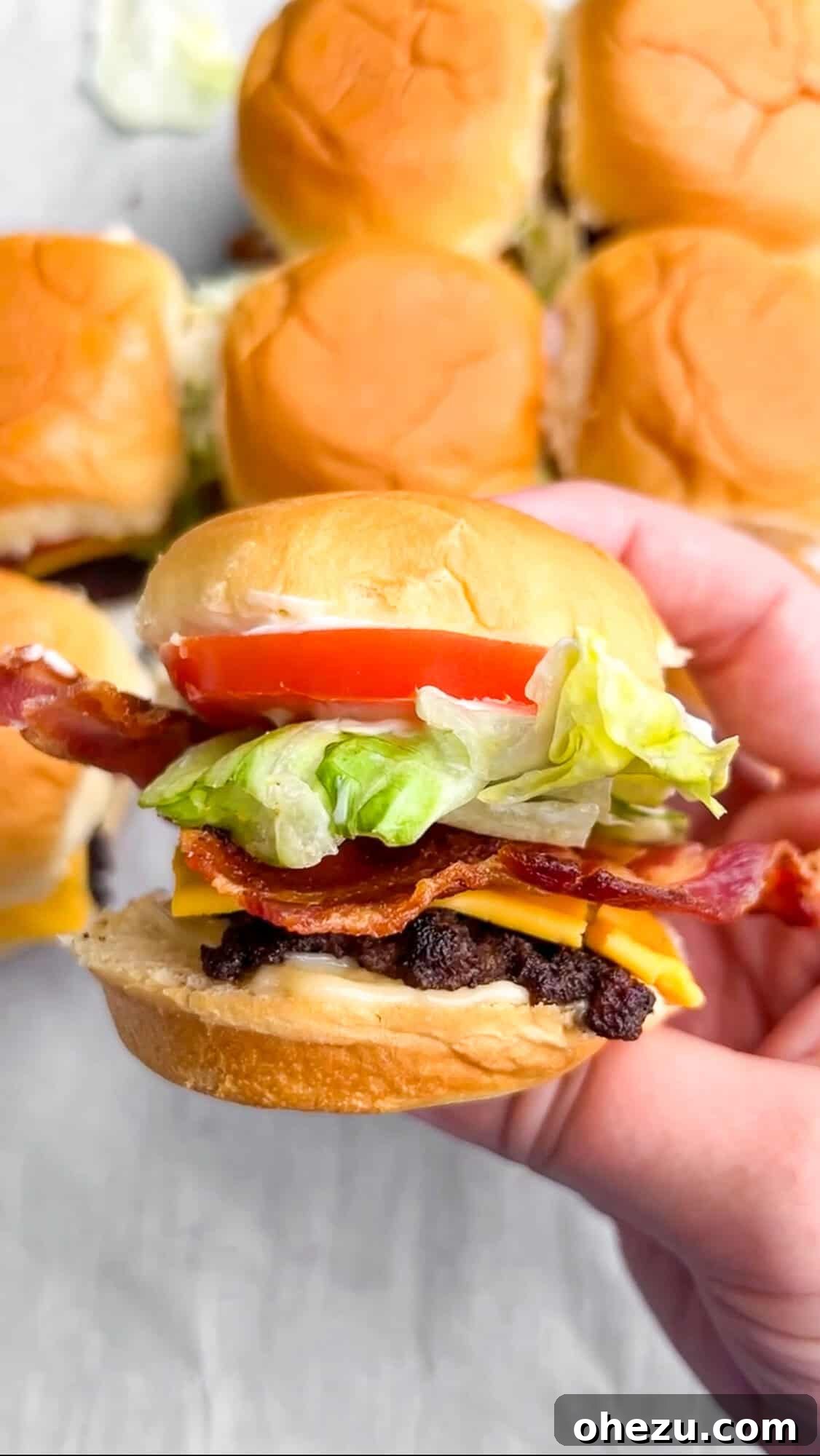 Plate of Jr Bacon Cheeseburger sliders with melted cheese and crispy bacon, perfect for a party.