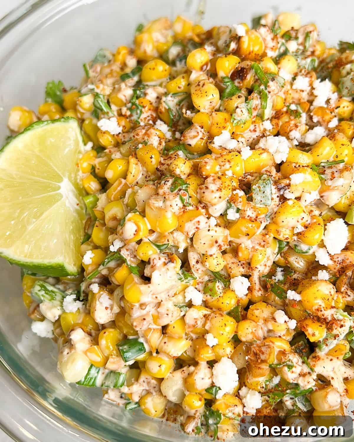 A bowl of fresh and flavorful Street Corn Salad, garnished with cilantro and lime.