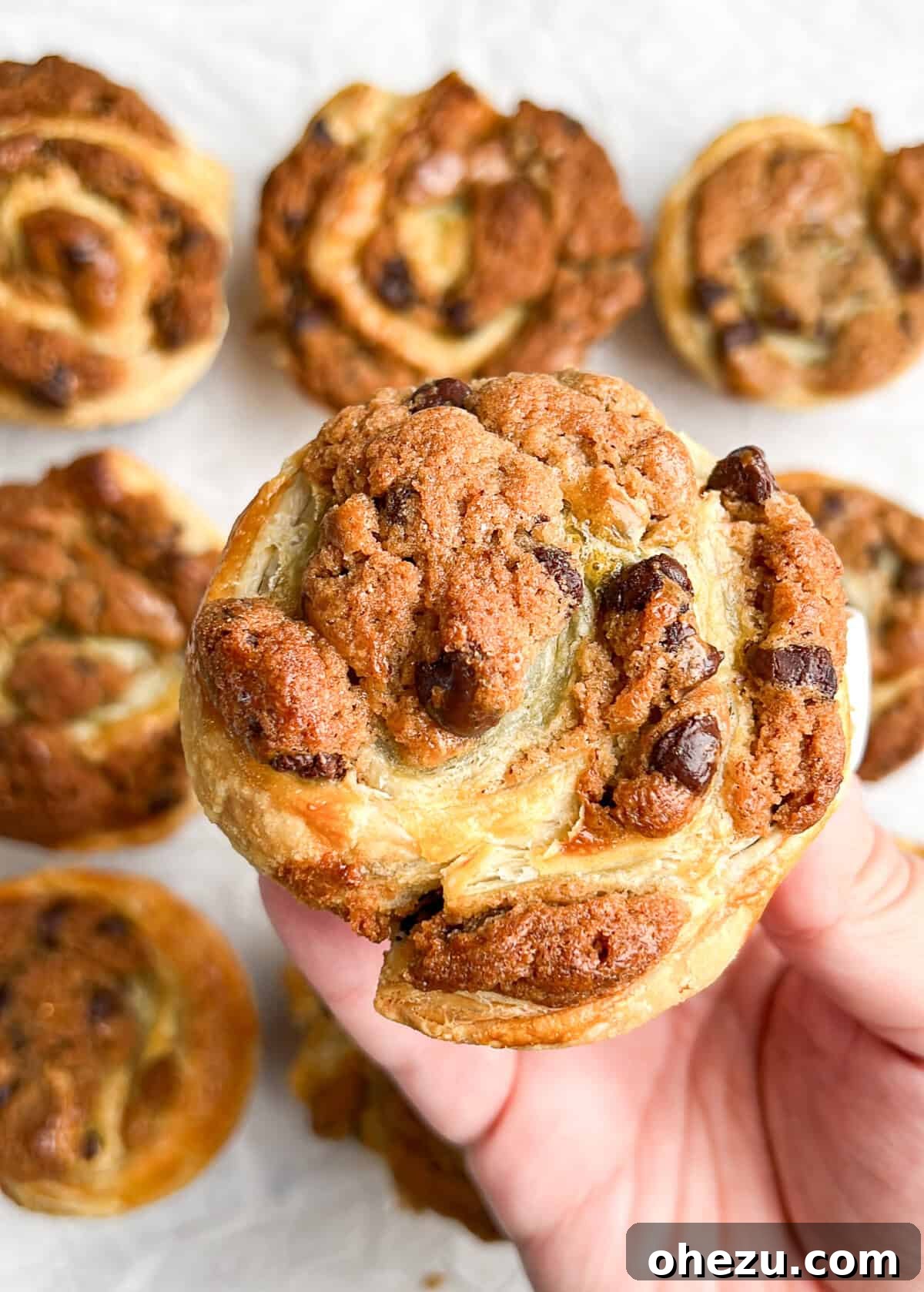 Golden-brown Cookie Puff Pastries in a muffin tin, garnished with powdered sugar.