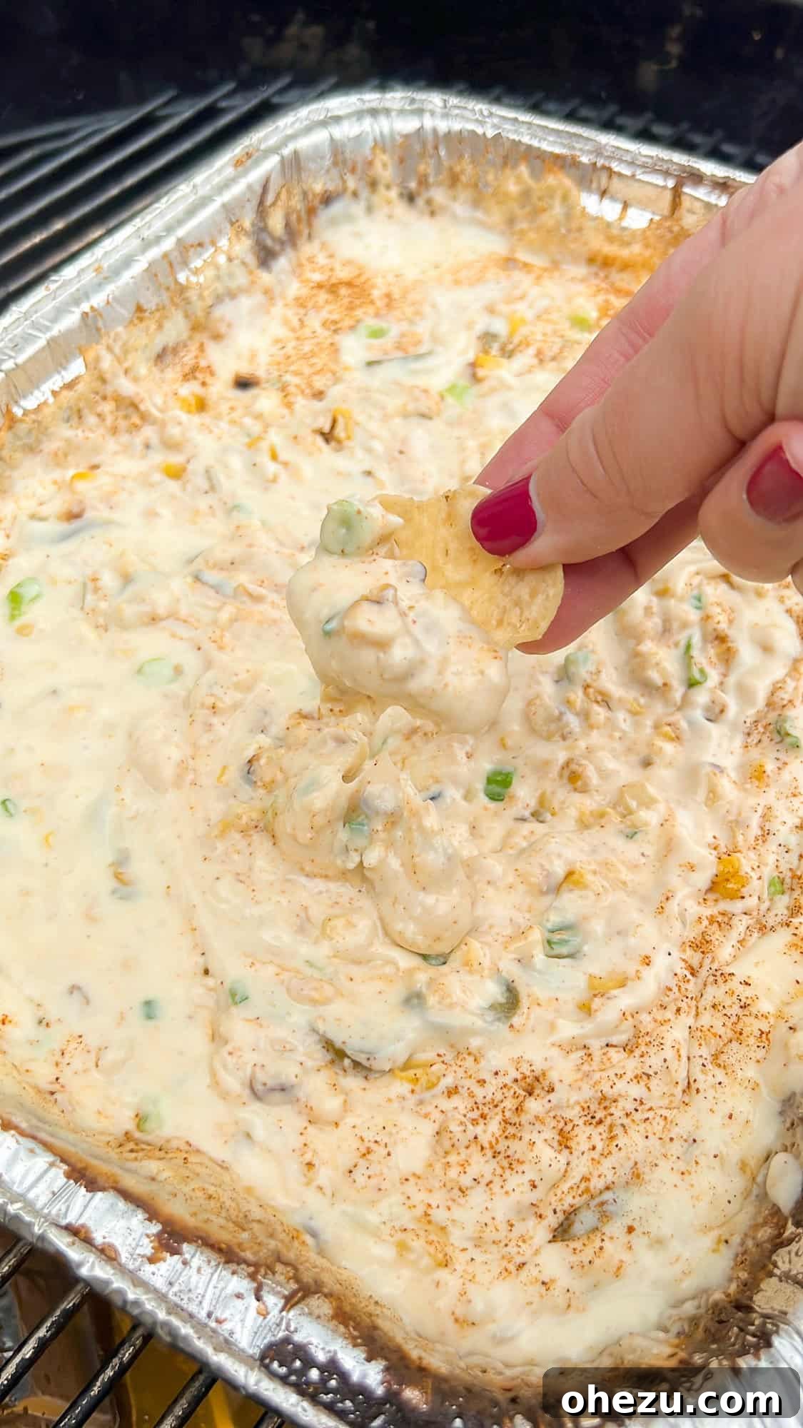 Creamy Elote Beer Smoked Queso dip served with tortilla chips, perfect for a summer party.