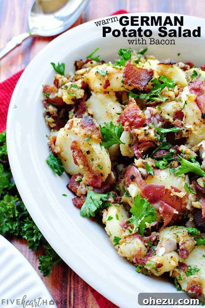 Warm German Potato Salad with bacon and herbs in a serving bowl.