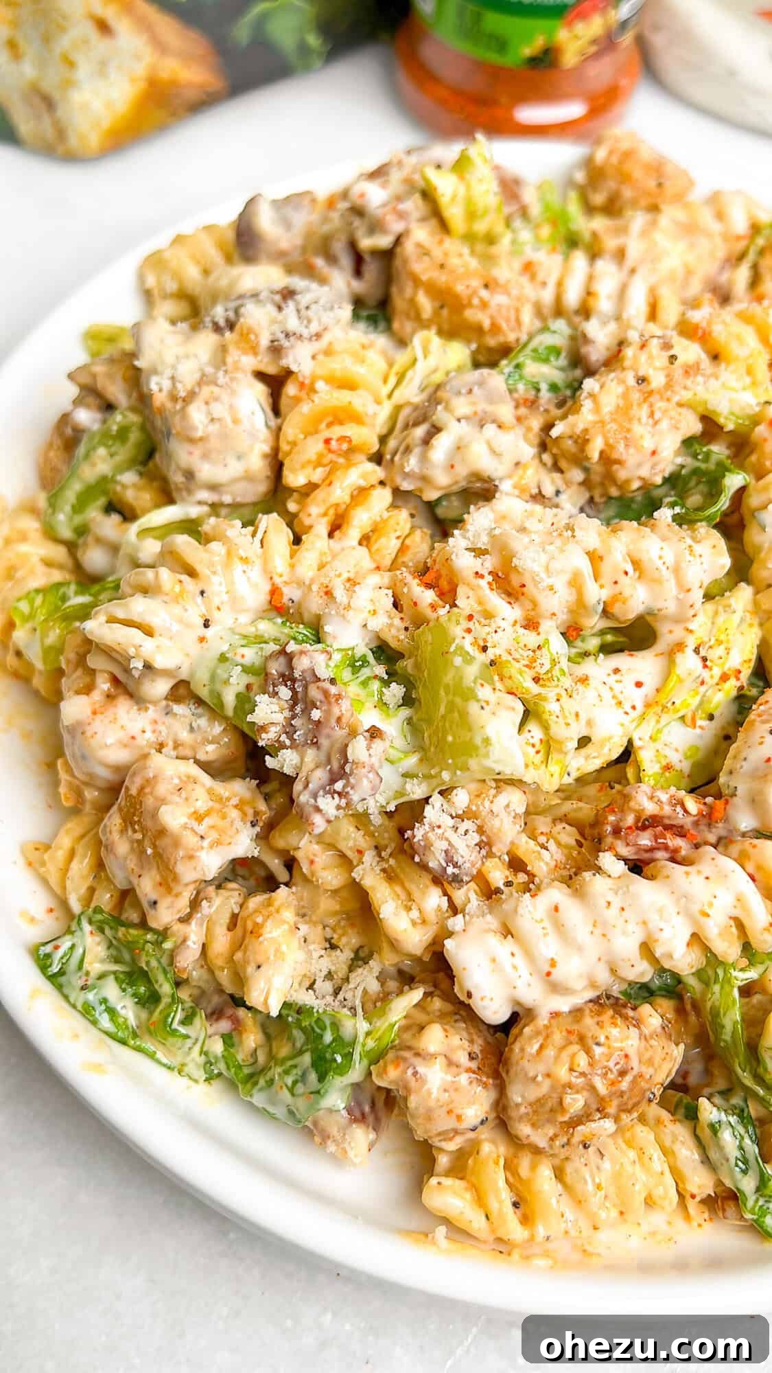A large bowl of Chicken Caesar Pasta Salad with grilled chicken, bacon, and croutons.