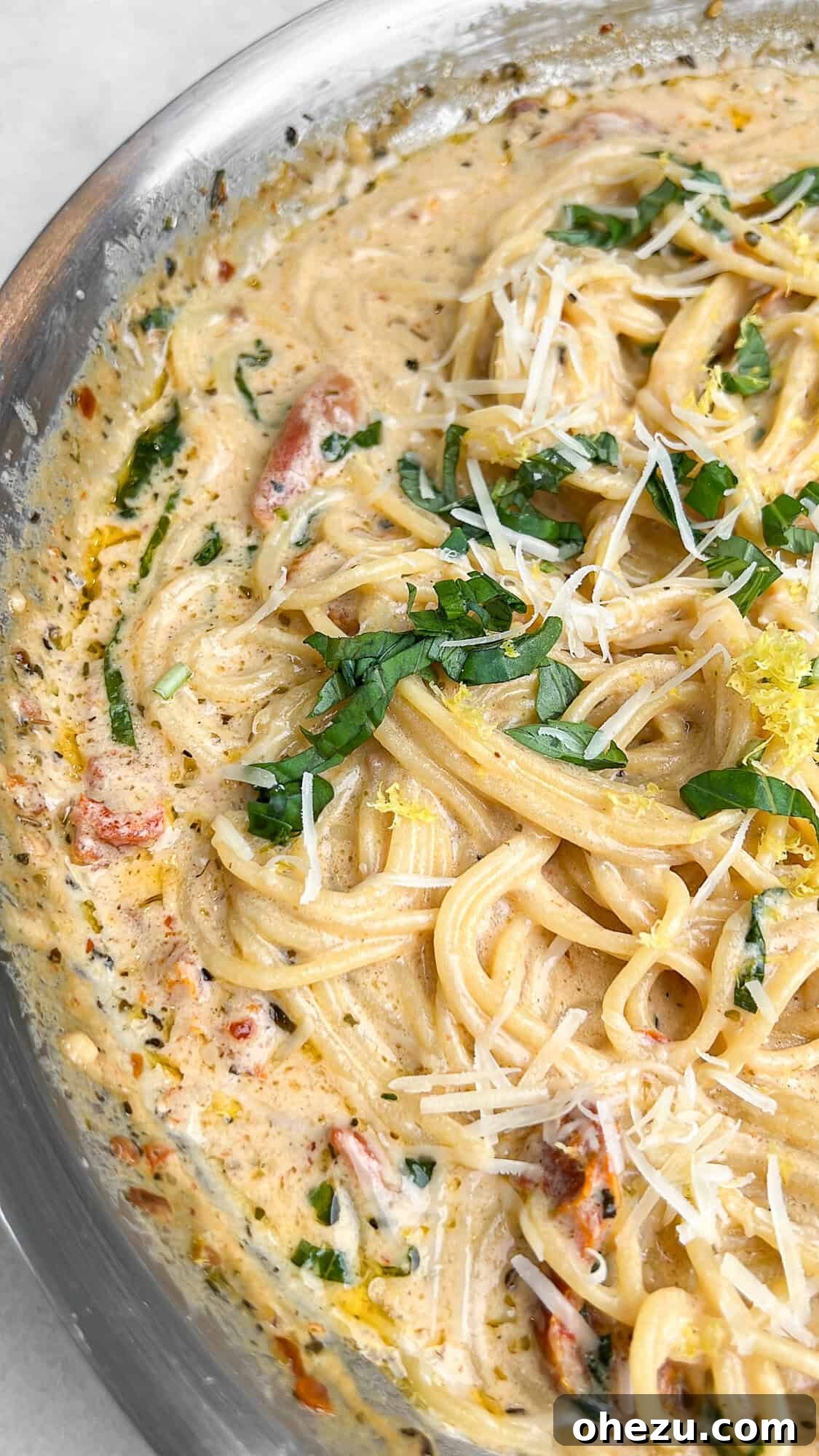 Tuscan Skillet Cream Pasta 3 One-pot creamy Tuscan pasta with fresh basil and lemon slices on a kitchen counter, ready to be served.