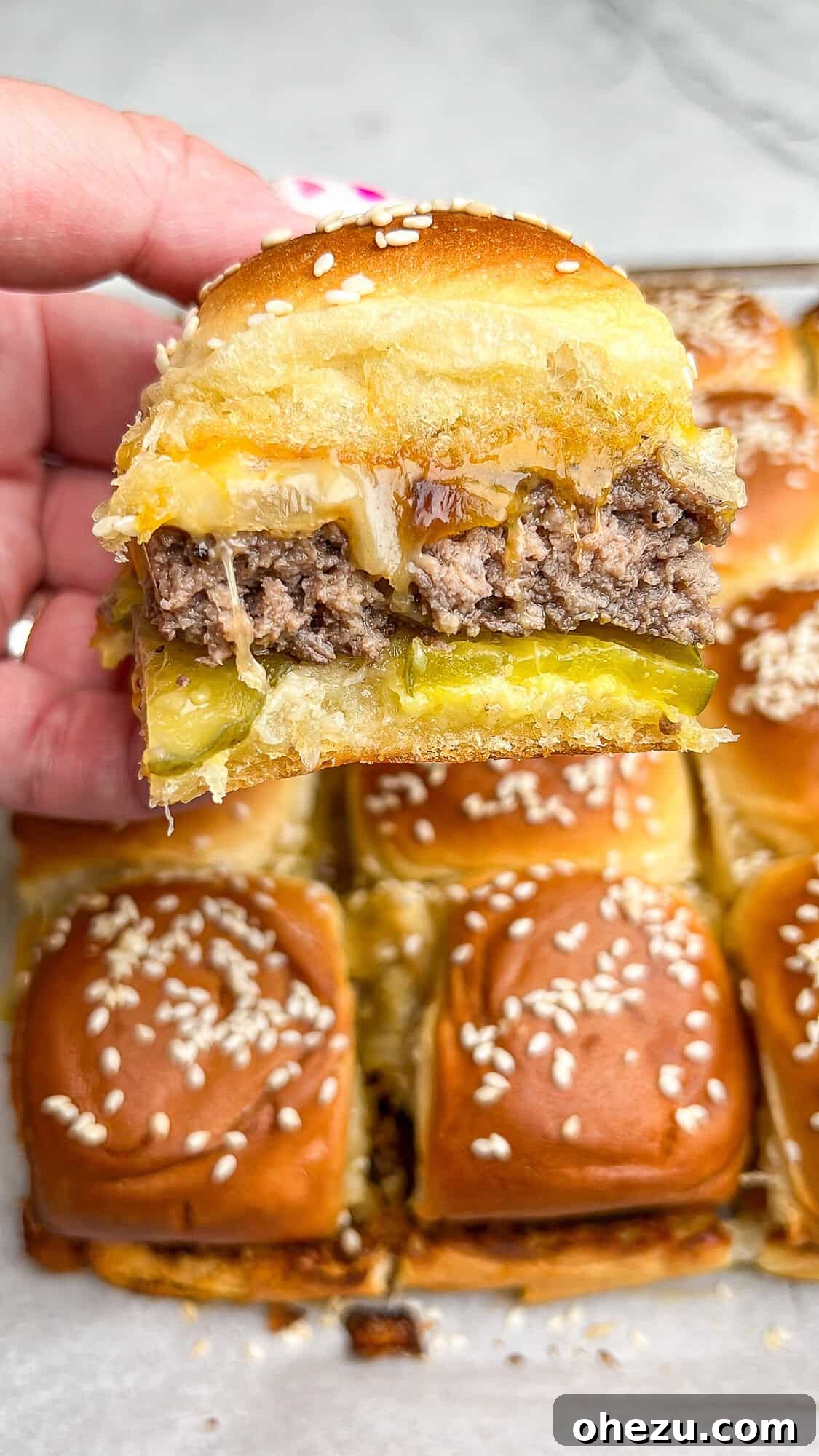 25 Effortless Meals for Busy School Days 9 A hand holding a delicious Hawaiian Roll Cheeseburger Slider with melted cheese