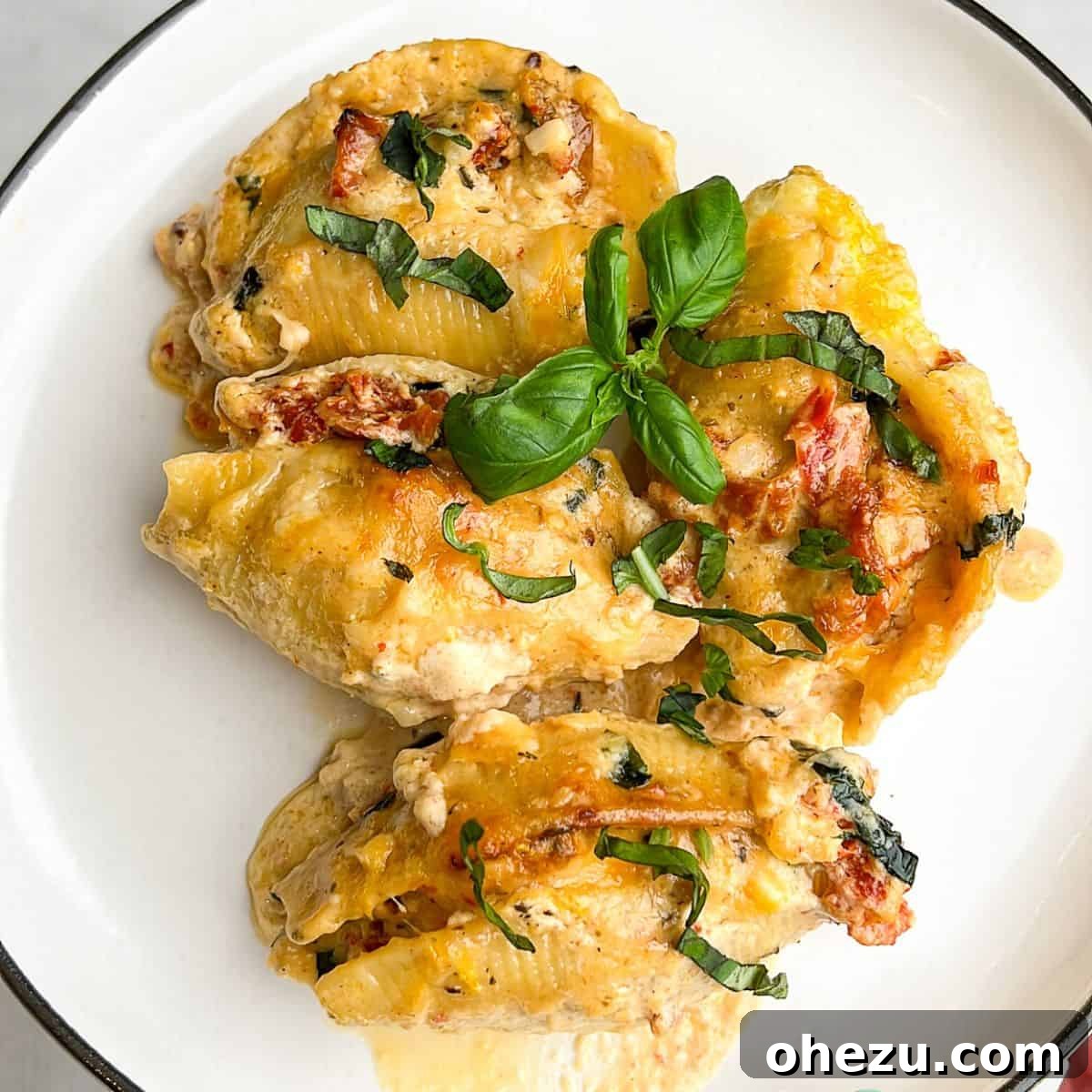 An exquisite close-up of Marry Me Chicken Stuffed Shells, beautifully presented and garnished. An inviting close-up of Marry Me Chicken Stuffed Shells served on a plate, garnished with fresh basil.