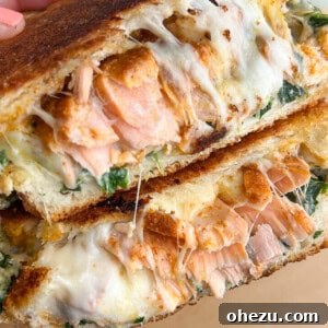 A salmon grilled cheese sandwich, cut in half to reveal the inside.