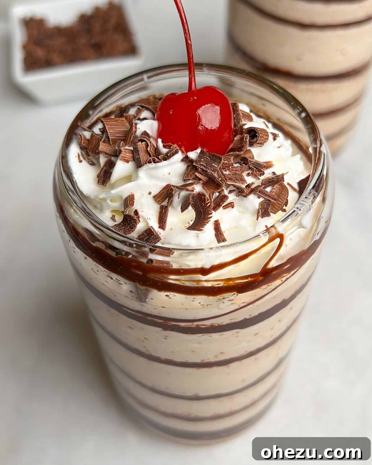An up-close shot of a Frozen Mudslide cocktail, showing the swirl of chocolate syrup inside the glass and a generous dollop of whipped cream on top.
