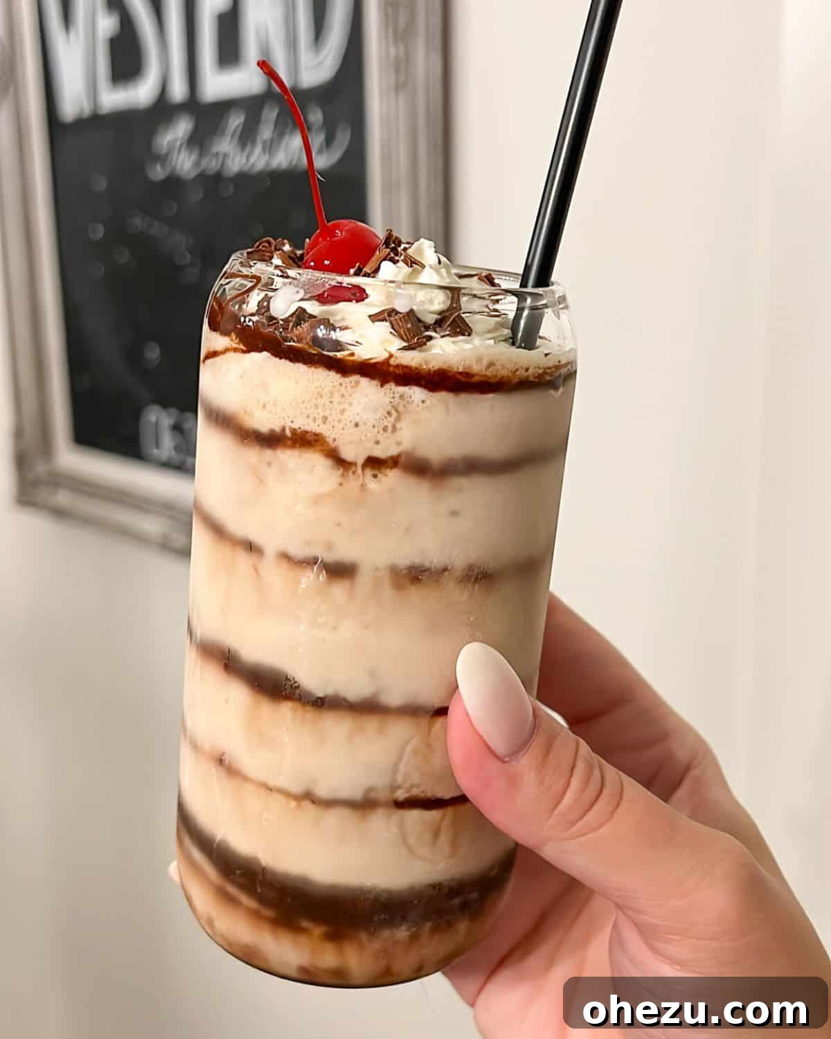 A hand holding a garnished frozen mudslide cocktail, emphasizing the rich texture and appealing presentation.