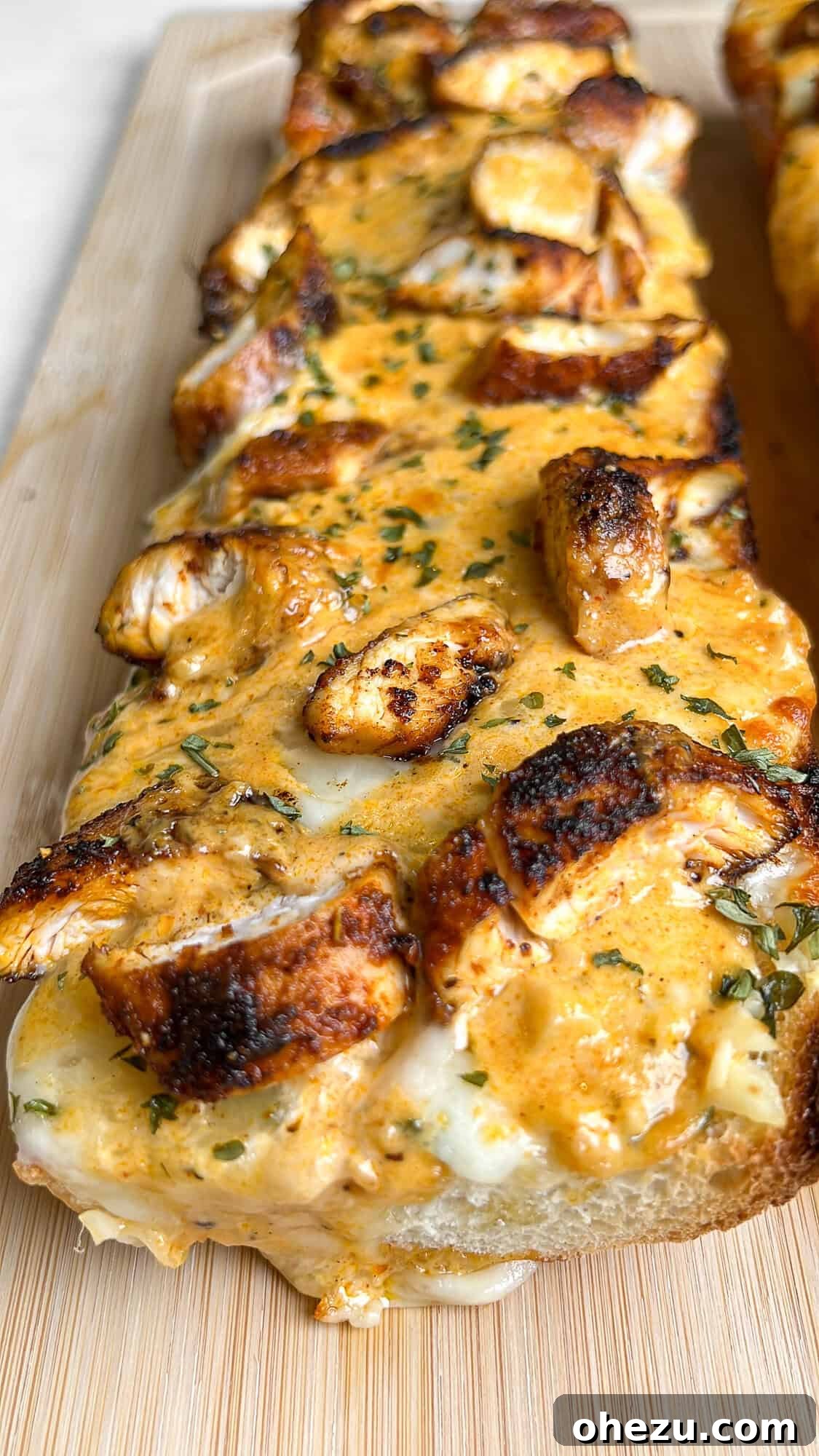 Chicken Alfredo Garlic Bread on a cutting board, garnished with fresh parsley.
