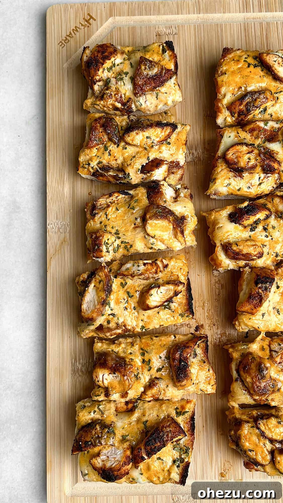 Chicken Alfredo Garlic Bread on a cutting board, neatly sliced into serving pieces.
