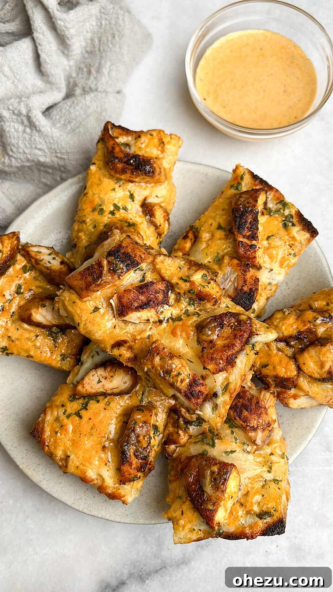 Multiple pieces of chicken alfredo garlic bread stacked on a white plate, ready to serve.