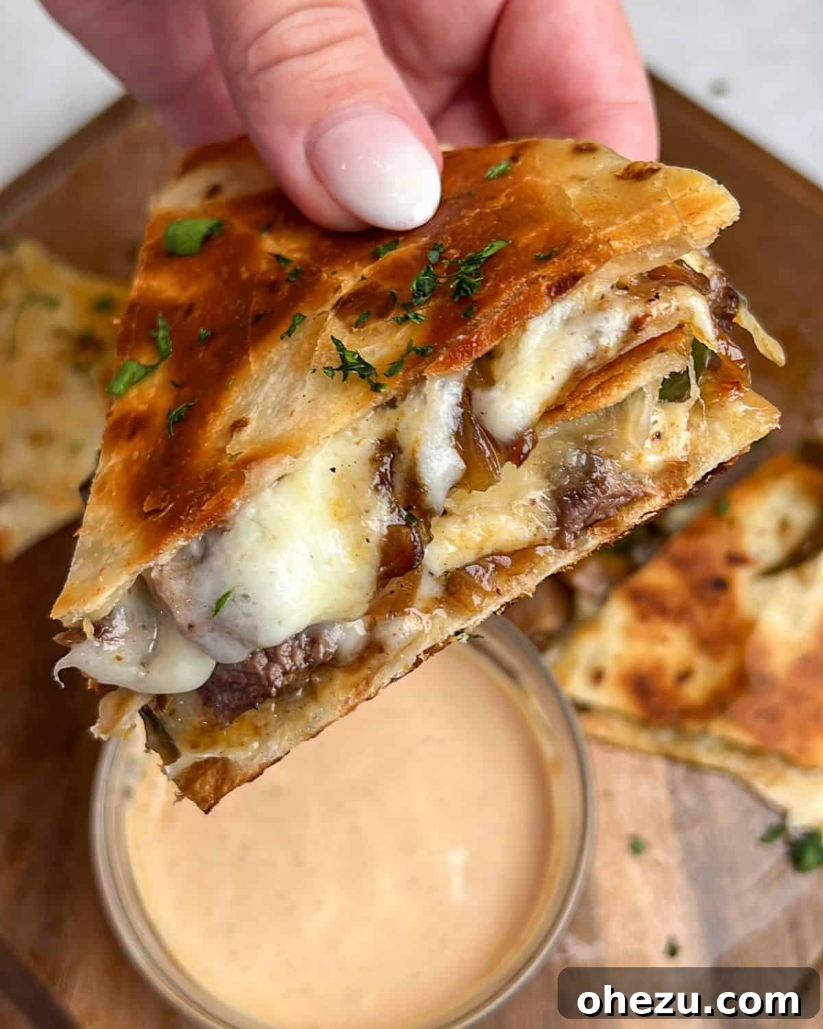 Smoky Steak Quesadillas with Creamy Chipotle Drizzle 2 A hand holding a perfectly cooked steak quesadilla, showing the crispy tortilla and a peek of the flavorful filling.