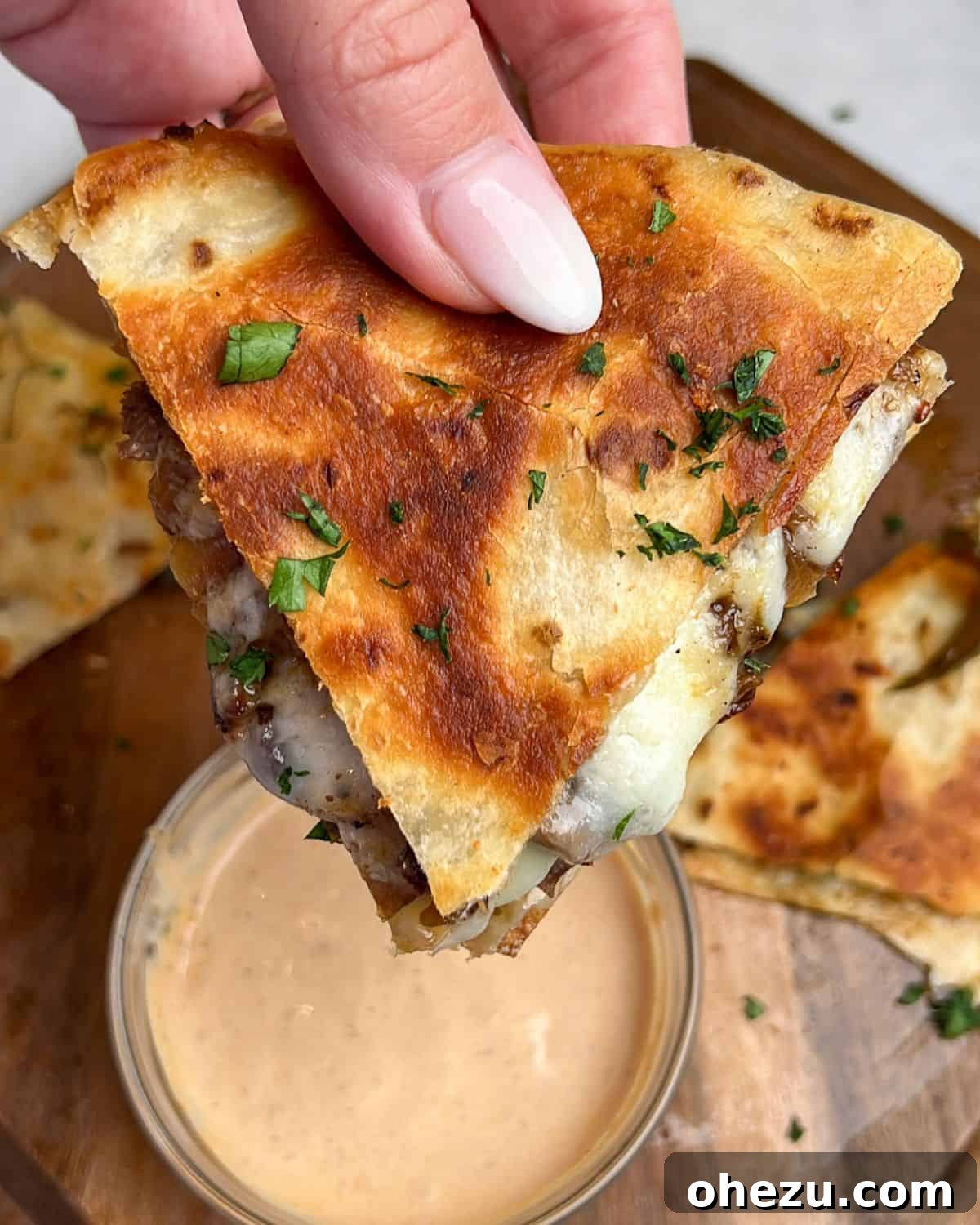 Smoky Steak Quesadillas with Creamy Chipotle Drizzle 6 Close-up of a hand holding a perfectly cooked steak quesadilla, ready to be enjoyed.