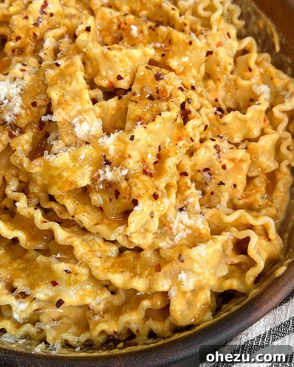 Creamy Pumpkin Alfredo pasta with hot honey drizzle in a white bowl, garnished with fresh herbs