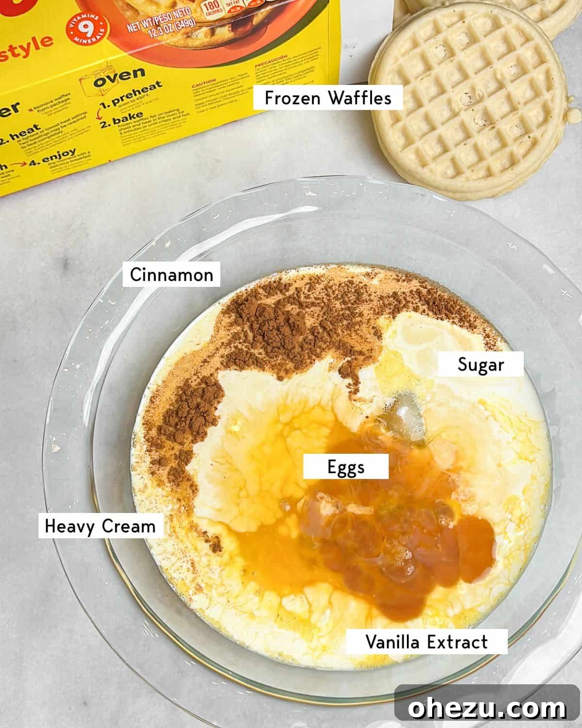 A flat lay image displaying all the key ingredients needed to make delicious French toast waffles, including waffles, eggs, cream, sugar, vanilla, and cinnamon.