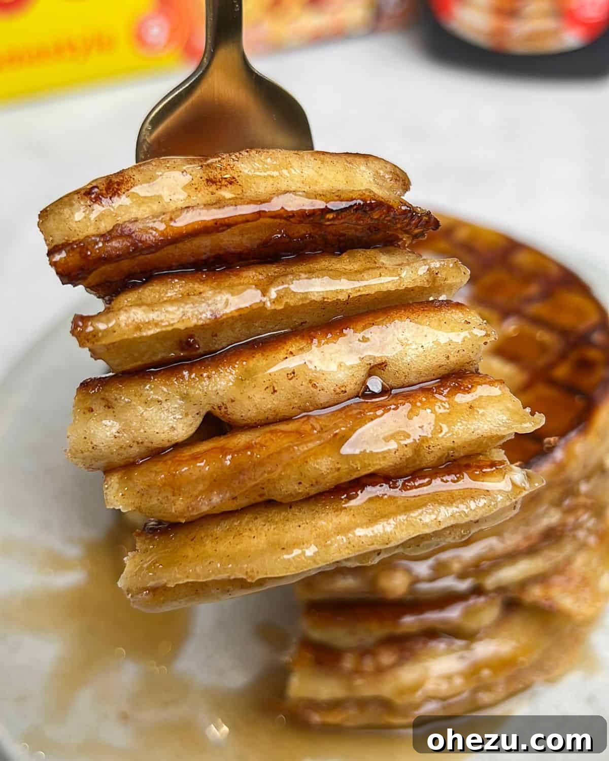 A close-up shot of a fork lifting a single bite of French toast waffle, showcasing its fluffy interior and golden crust, ready to be eaten.