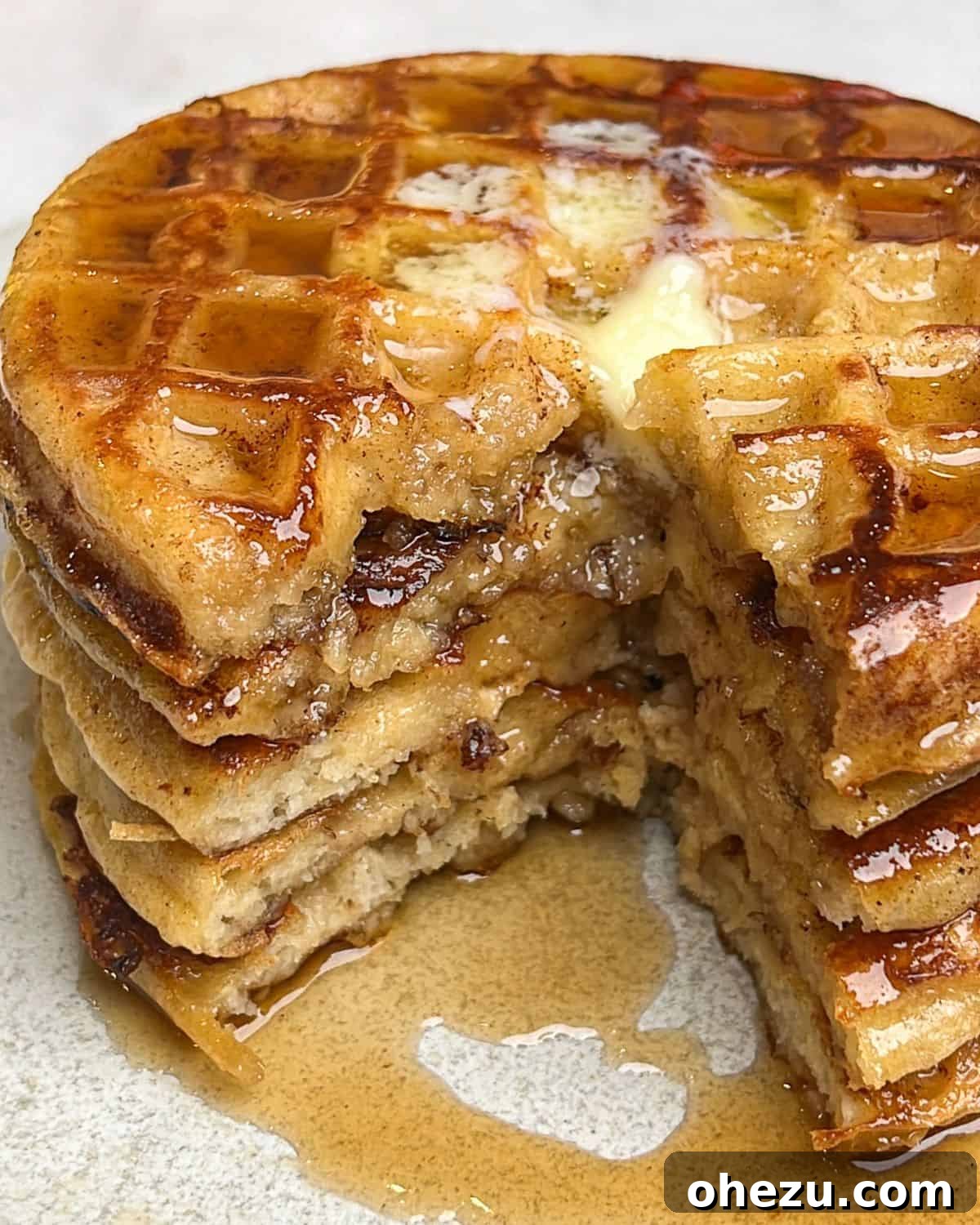 A stack of French toast waffles with a visible bite taken out of the top waffle, highlighting its delicious texture and inviting appeal.