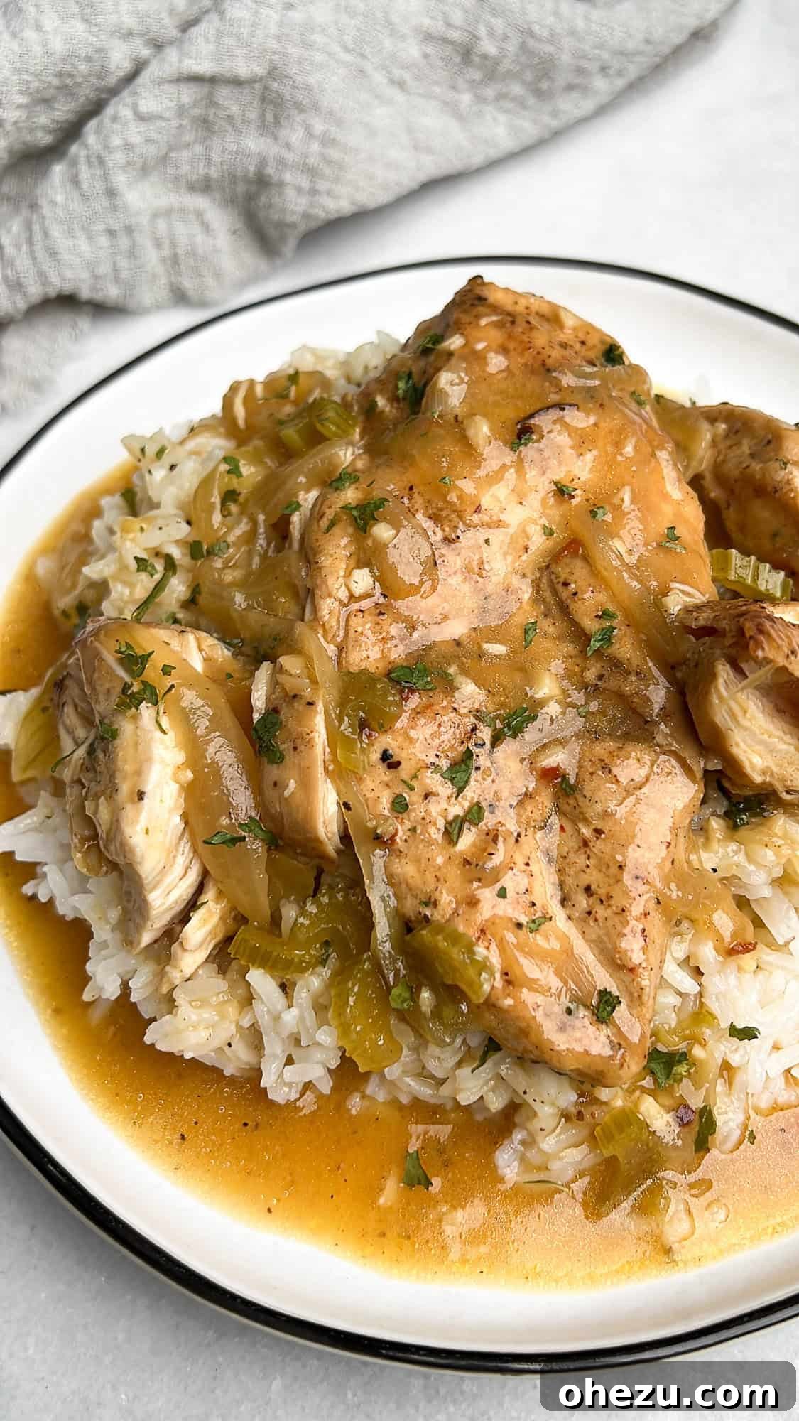 This slow cooker smothered chicken, with its creamy gravy and melt-in-your-mouth texture, is the ultimate cozy meal. And it's so easy! Smothered chicken served over rice with creamy gravy, garnished with fresh herbs.