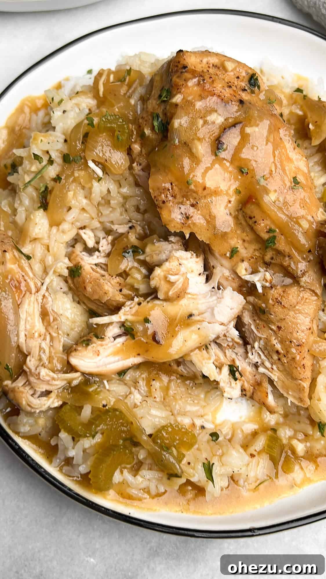 This slow cooker smothered chicken, with its creamy gravy and melt-in-your-mouth texture, is the ultimate cozy meal. And it's so easy! Overhead image of slow cooker smothered chicken, generously plated over fluffy white rice with rich, golden gravy.