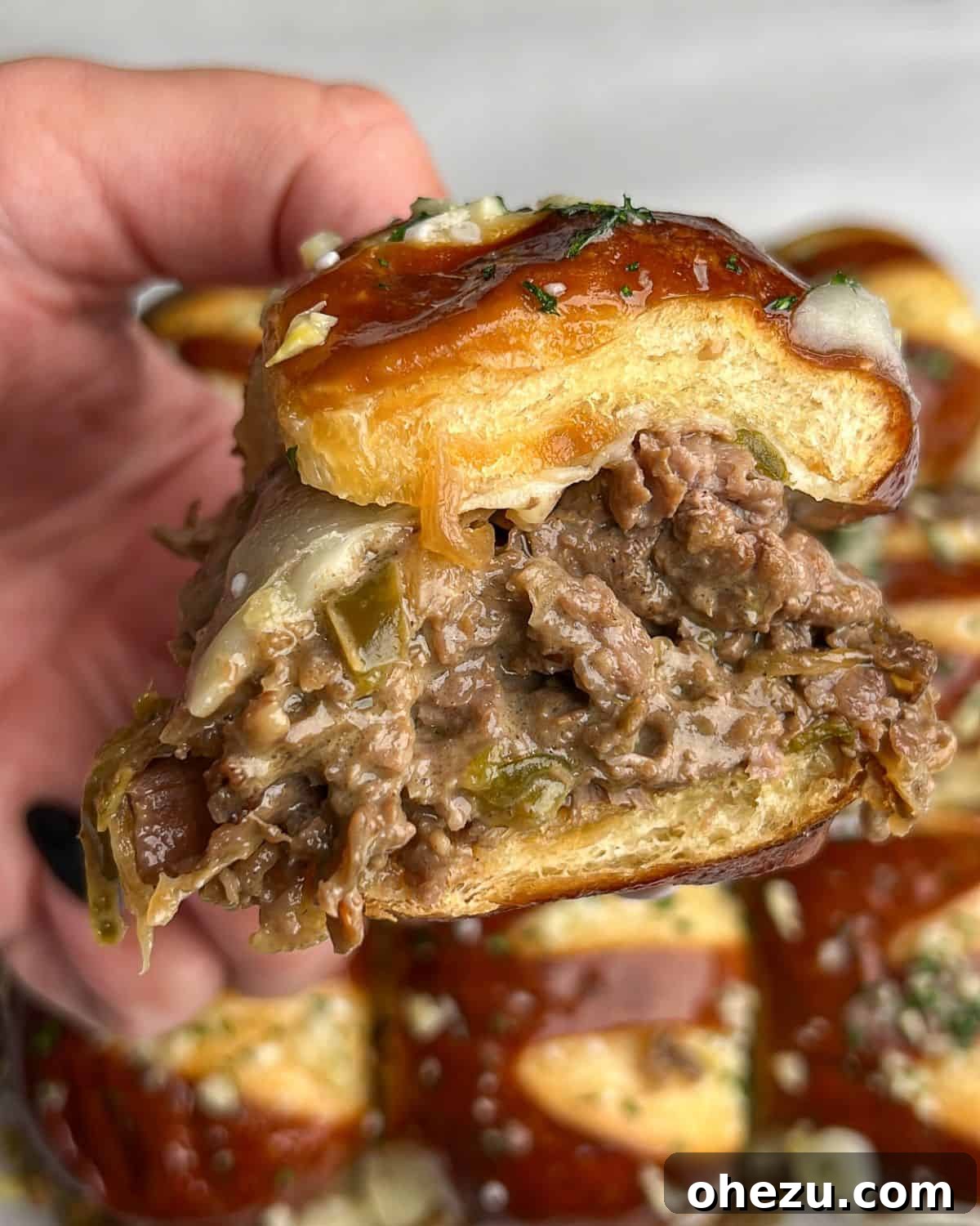 A tantalizing close-up image of a single Philly cheesesteak slider, showcasing the melted cheese, juicy steak, and soft bun.