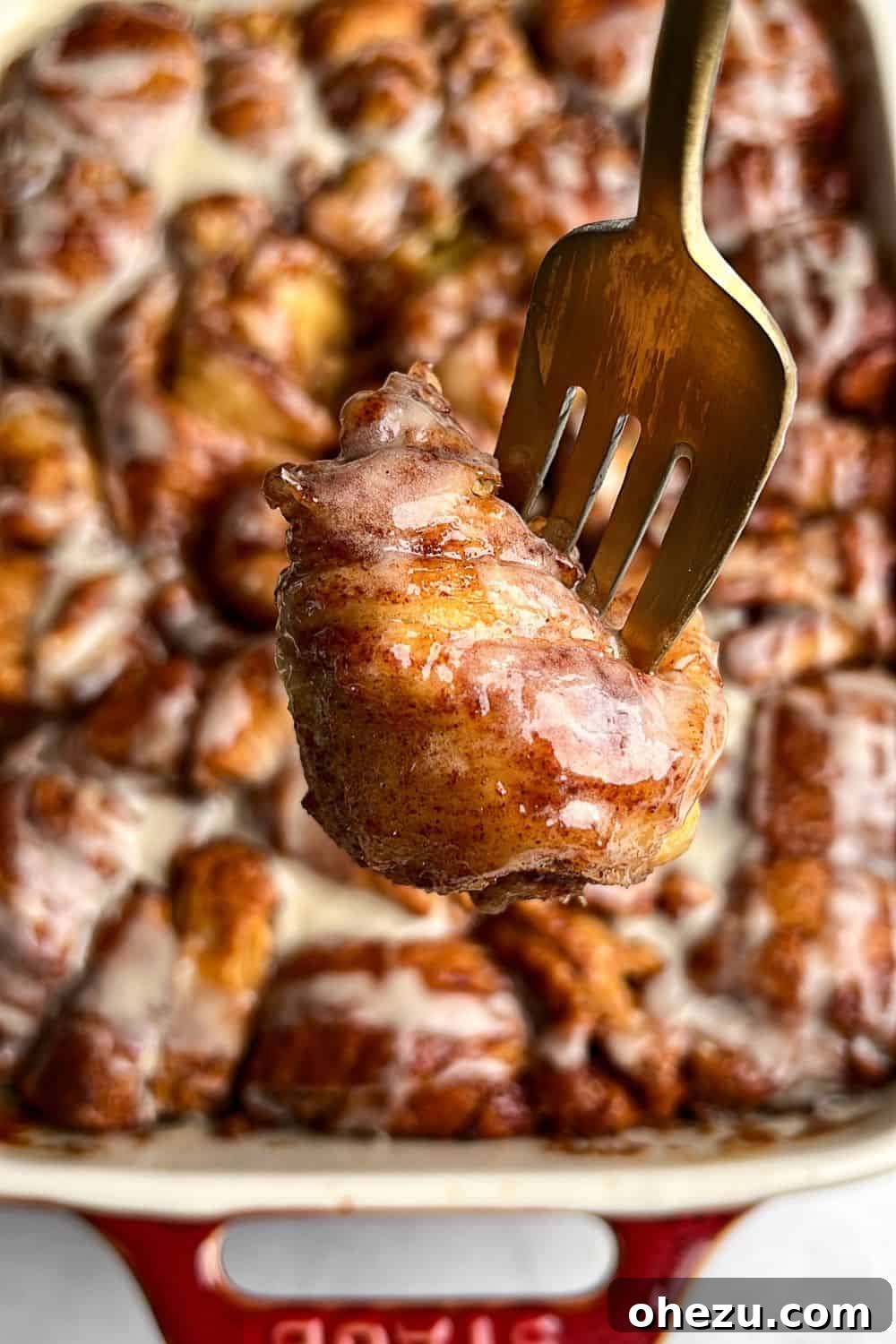 This shortcut recipe uses store-bought dough to create warm, buttery cinnamon roll bites in under an hour. You won't be able to resist! A fork lifts a single, perfectly frosted cinnamon roll bite from a baking dish, showcasing its soft texture.