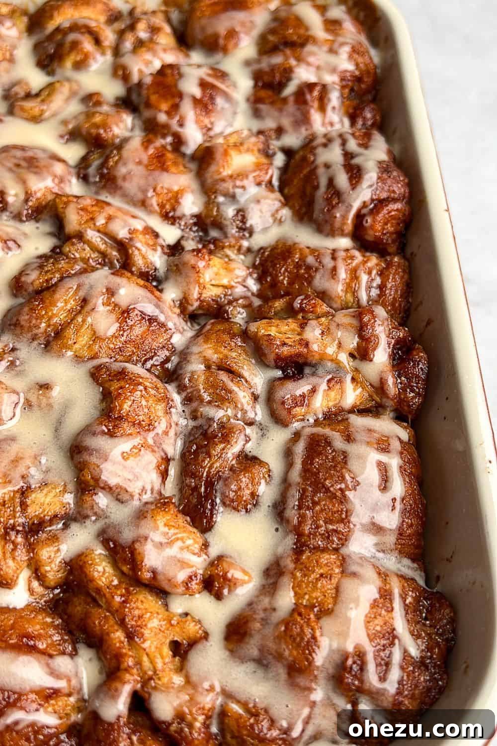 This shortcut recipe uses store-bought dough to create warm, buttery cinnamon roll bites in under an hour. You won't be able to resist! A vibrant, close-up shot of a baking pan brimming with warm, freshly baked cinnamon roll bites, glazed with frosting.
