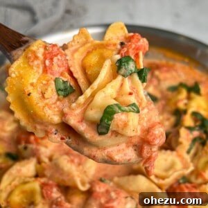 Creamy tomato pasta on a wooden spoon held up to the camera, showcasing the delicious sauce.